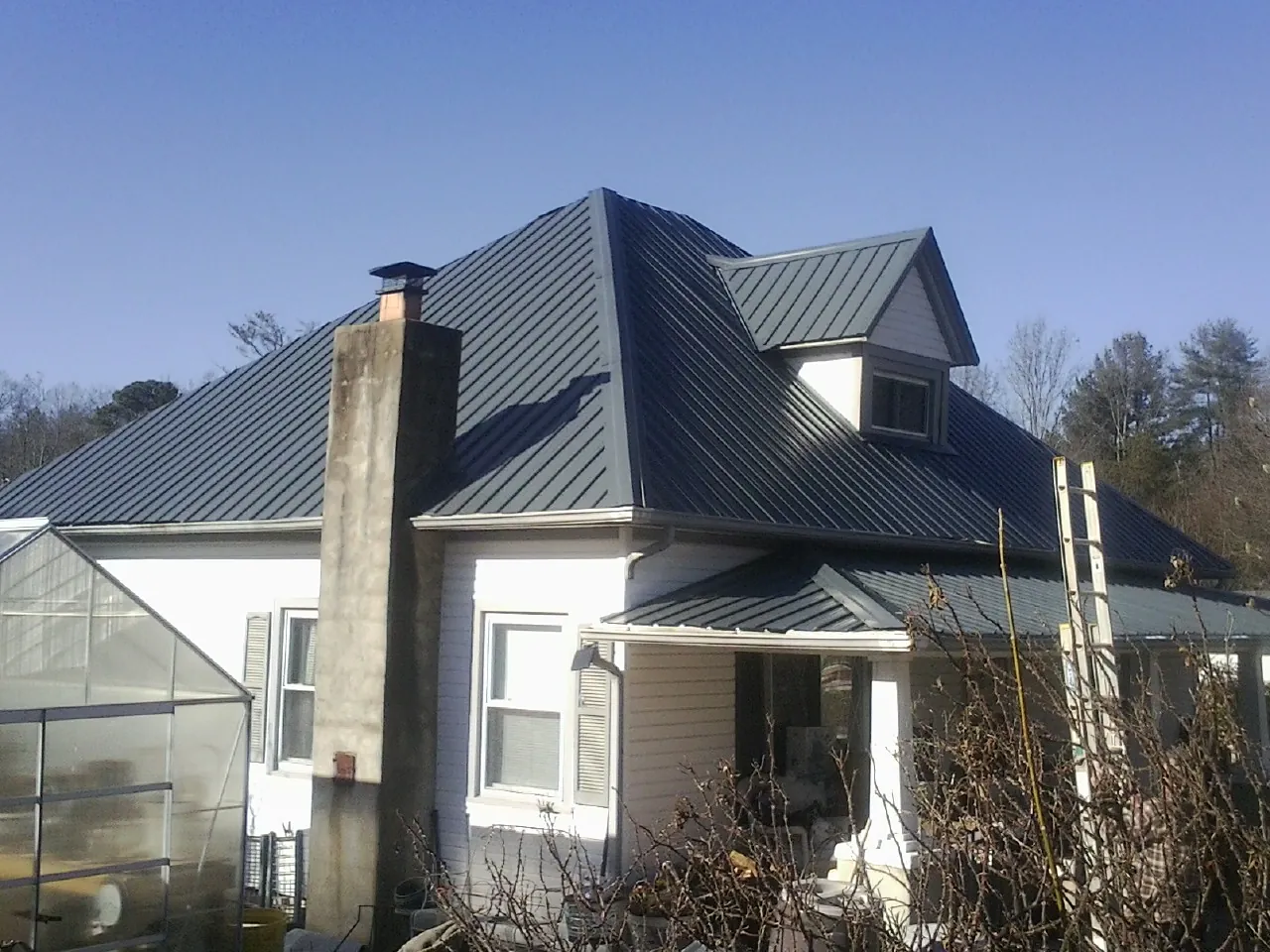 Dark blue standing seam metal roof on a white farmhouse with dormer — Slate & Tile Roof Repair by Roofing Brothers in Columbus City