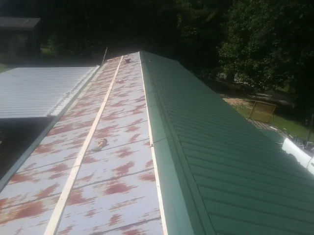 Old rusted panels beside newly installed green metal roofing — Wind Damage Roof Repair by Roofing Brothers in Columbus City