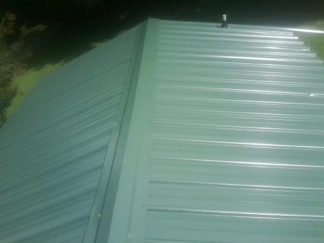 New green metal panels meeting at the ridge of a roof — Flat Roof Repair work by our crew in Columbus City
