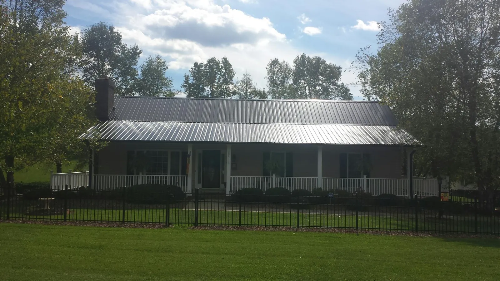 Gray metal roof on a brick ranch with a full width front porch — Gutter Guard Installation work by our crew in Columbus City