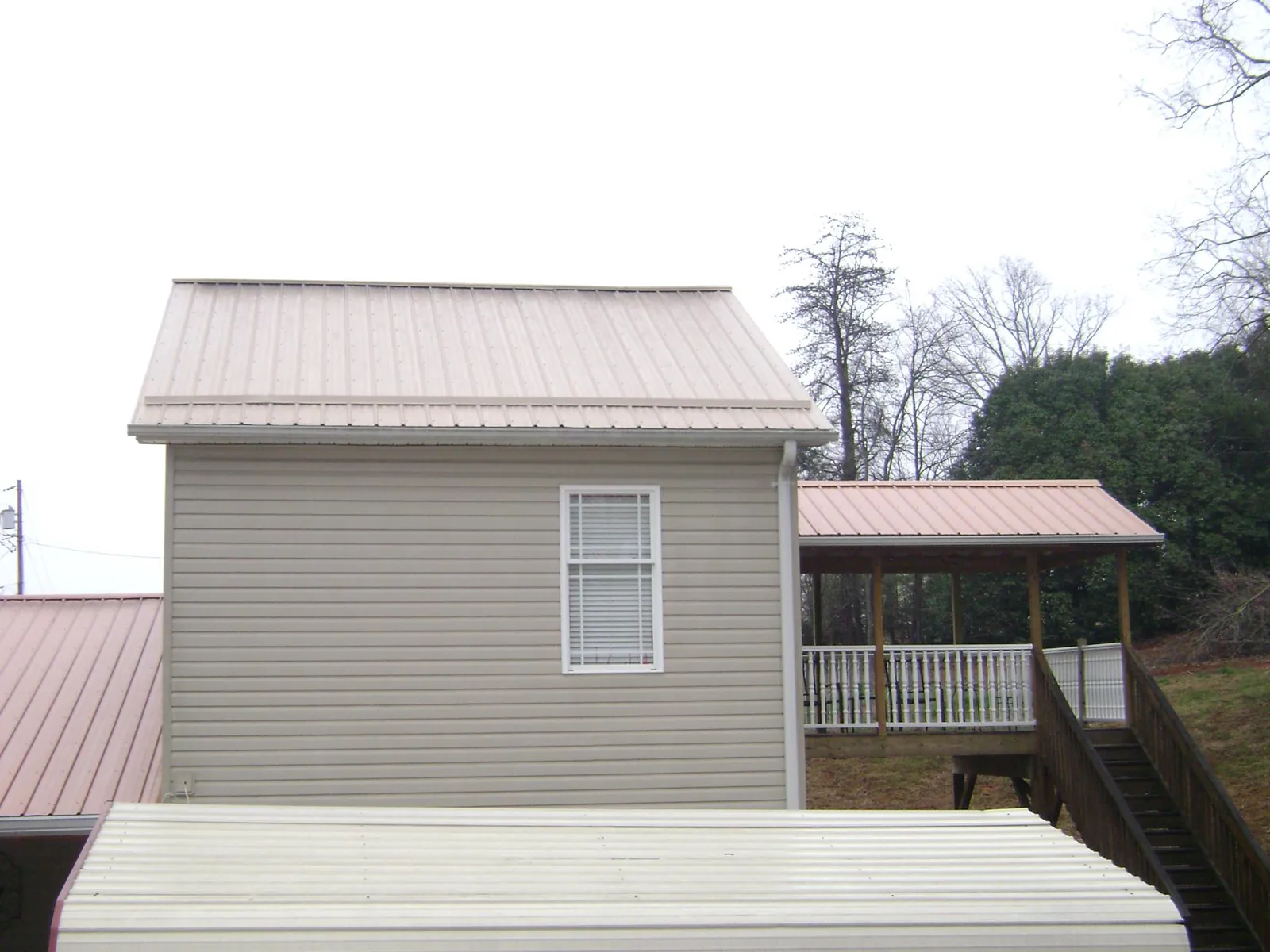 Tan metal roofs on a two story addition and attached porch, from a Roof Replacement job in Columbus City