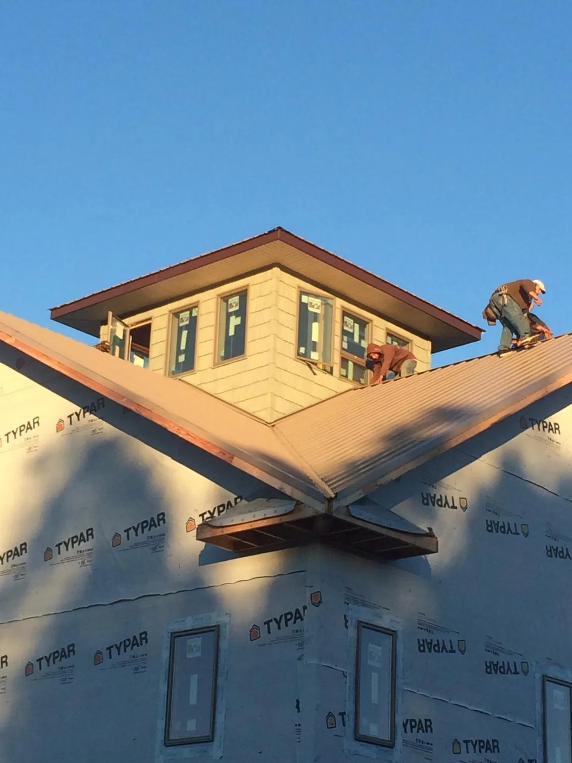 Roofers working around a rooftop cupola on a new metal roof at sunset — Roof Waterproofing in Columbus City by Roofing Brothers